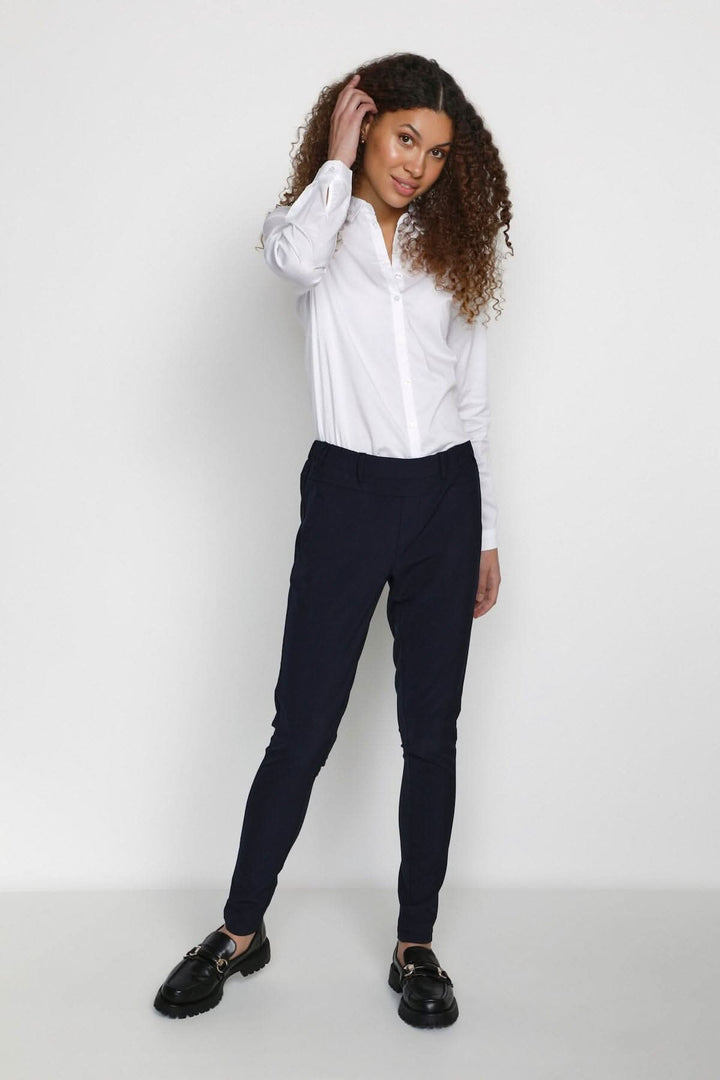 Femme avec une chemise blanche et un pantalon de tailleur Jillian Sofie, affichant un look chic pour le bureau.