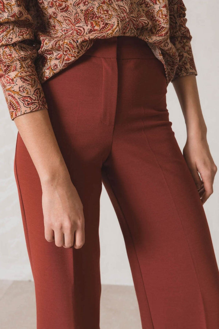 Pantalon habillé ample de couleur rouge, porté avec un haut à motifs, idéal pour un look chic et tendance.