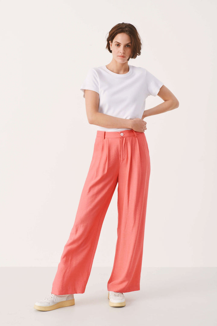 Pantalon habillé Sibille à jambe large, couleur corail, associé à un t-shirt blanc, style décontracté.
