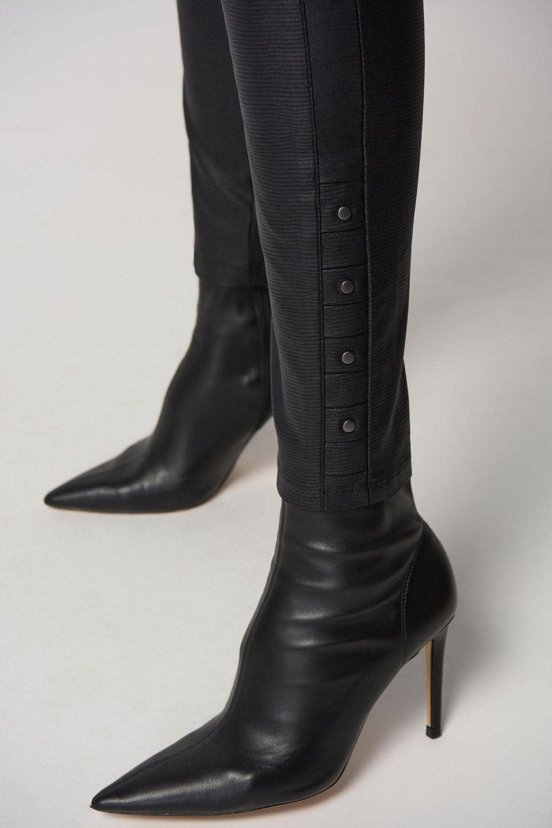 Pantalon skinny élégant avec boutons et talons aiguilles noirs, parfait pour un look chic et tendance.