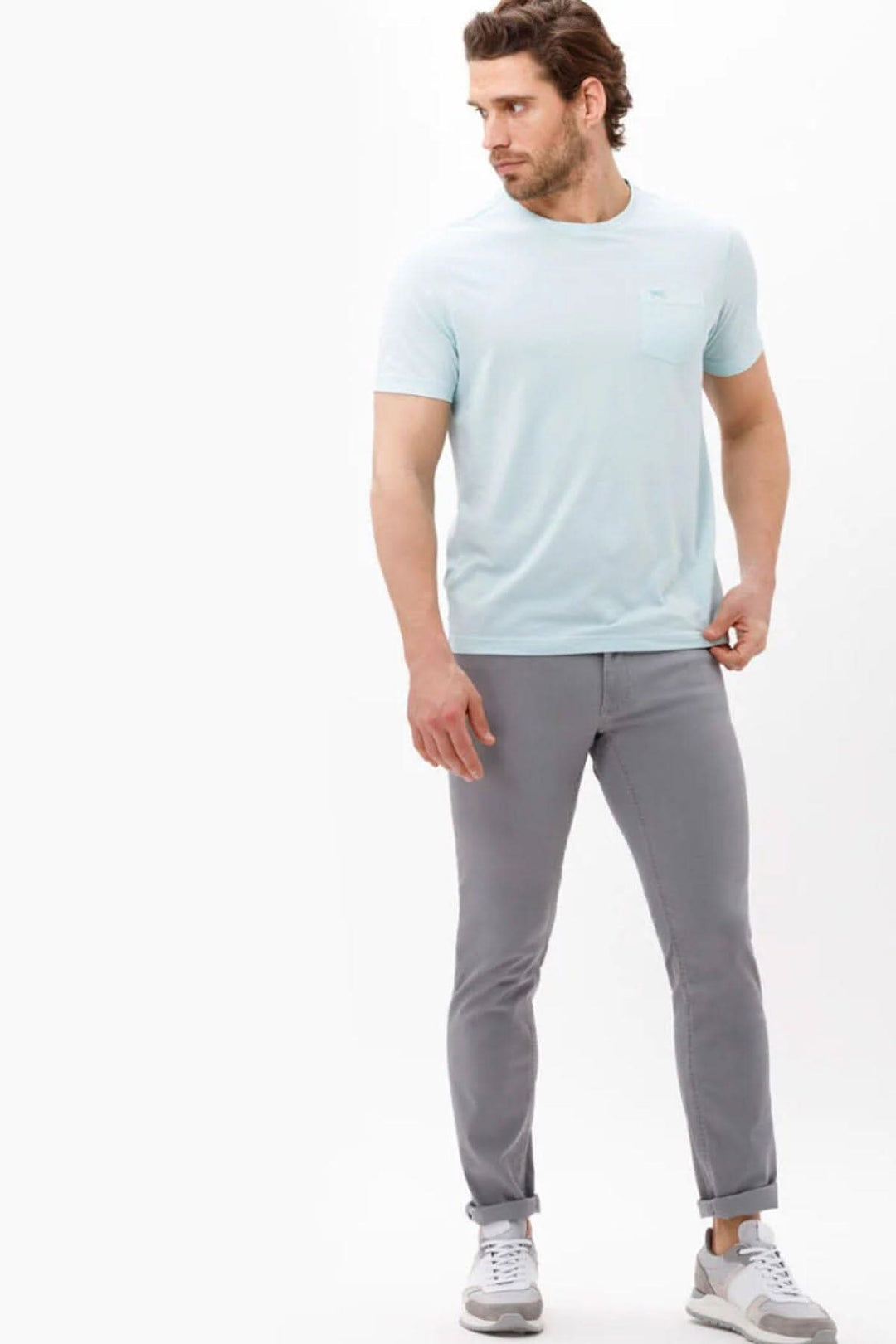 Homme portant un pantalon en coton gris et un t-shirt bleu clair, alliant confort et style moderne.