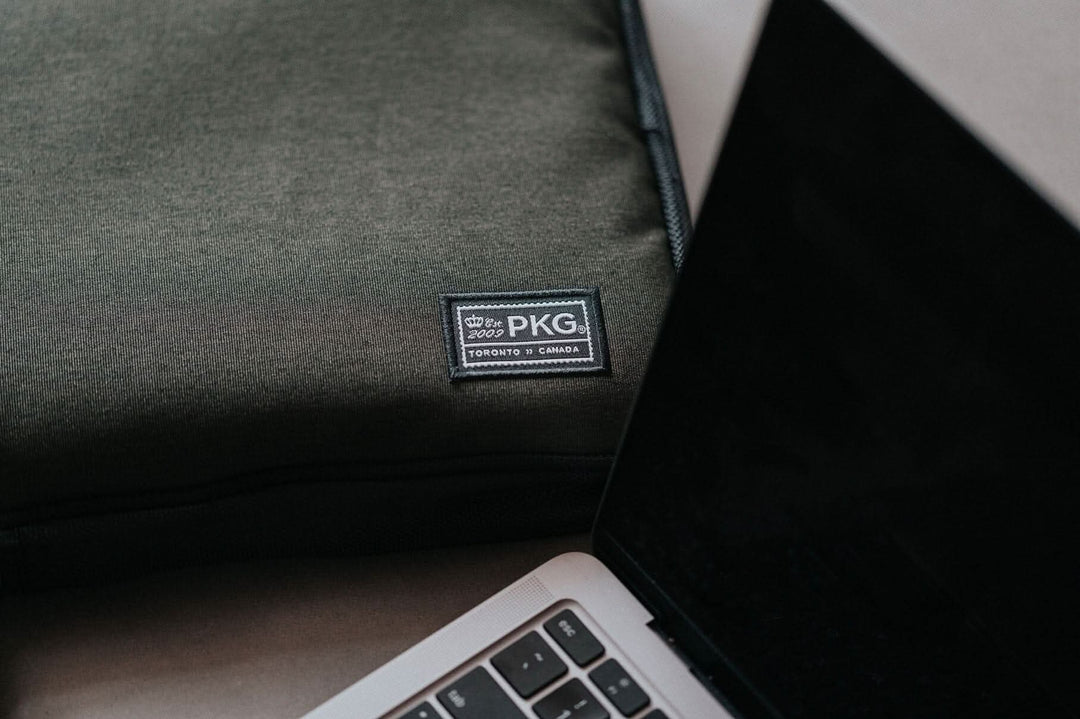 Pochette pour ordinateur portable PKG Stuff sur une surface avec un ordinateur portable à côté.