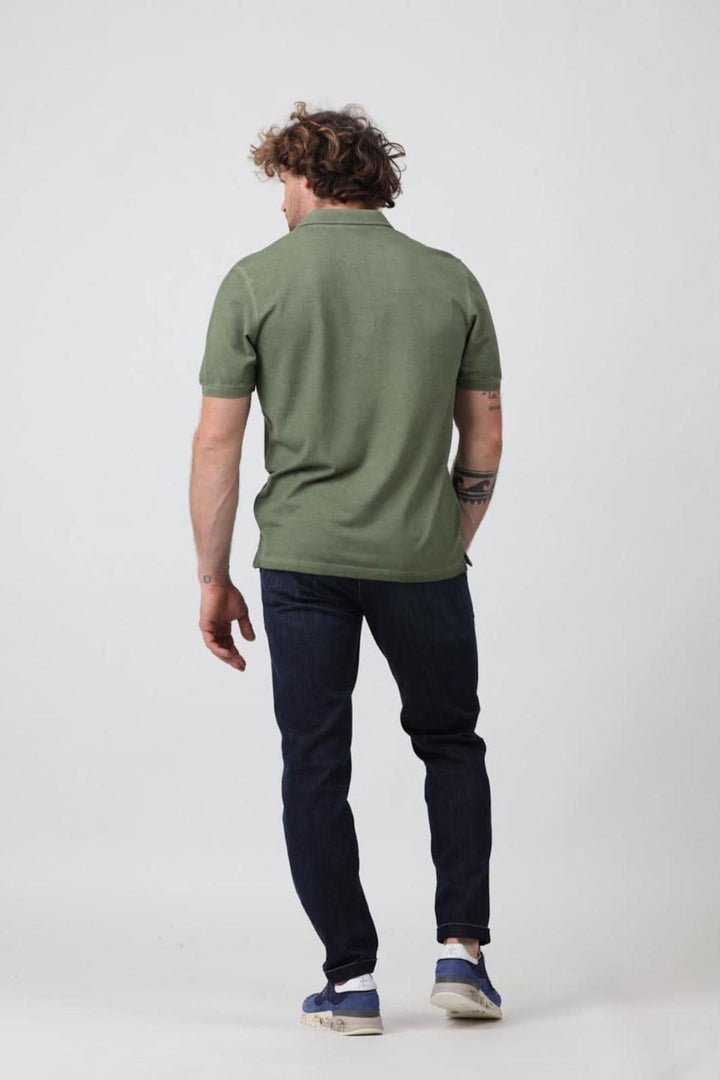 Homme de dos portant un polo à manches courtes vert avec col côtelé, associé à un jean foncé.