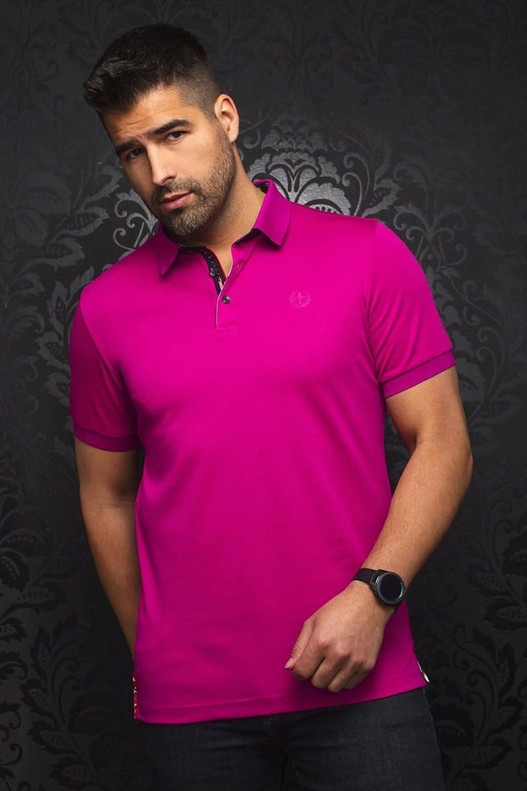 Homme portant un polo rose vif au col contrastant, avec broderie et détails sophistiqués.
