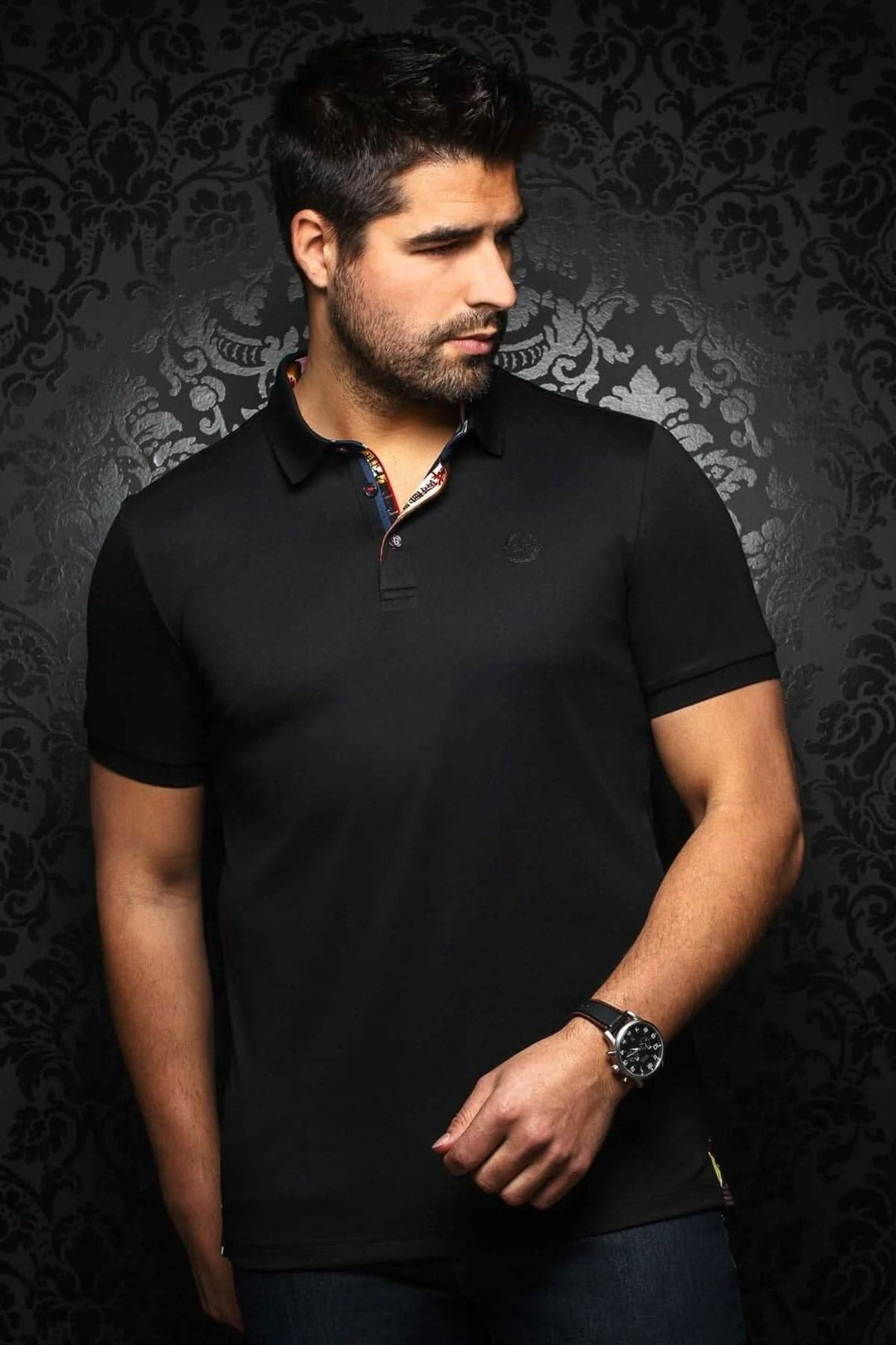 Homme portant un polo noir avec col contrastant et broderie élégante, mettant en avant un style habillé et décontracté.