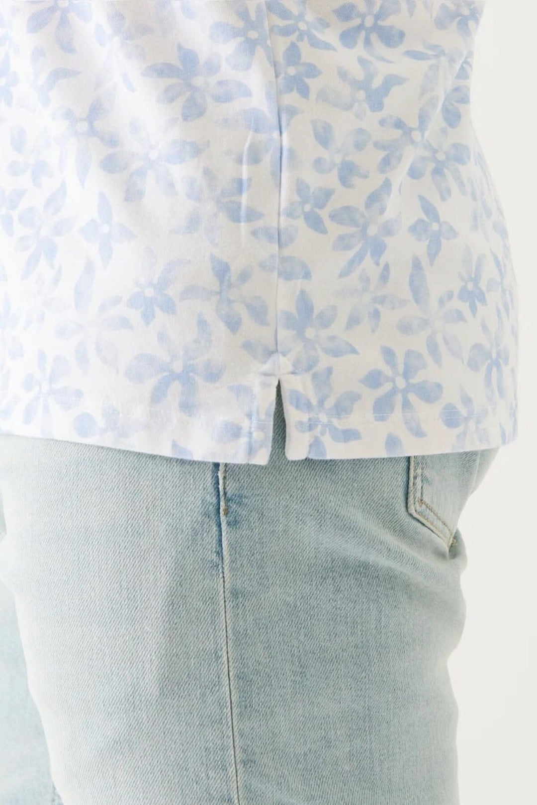 Polo imprimé en coton pima extensible avec motif floral bleu, porté avec un jean clair.
