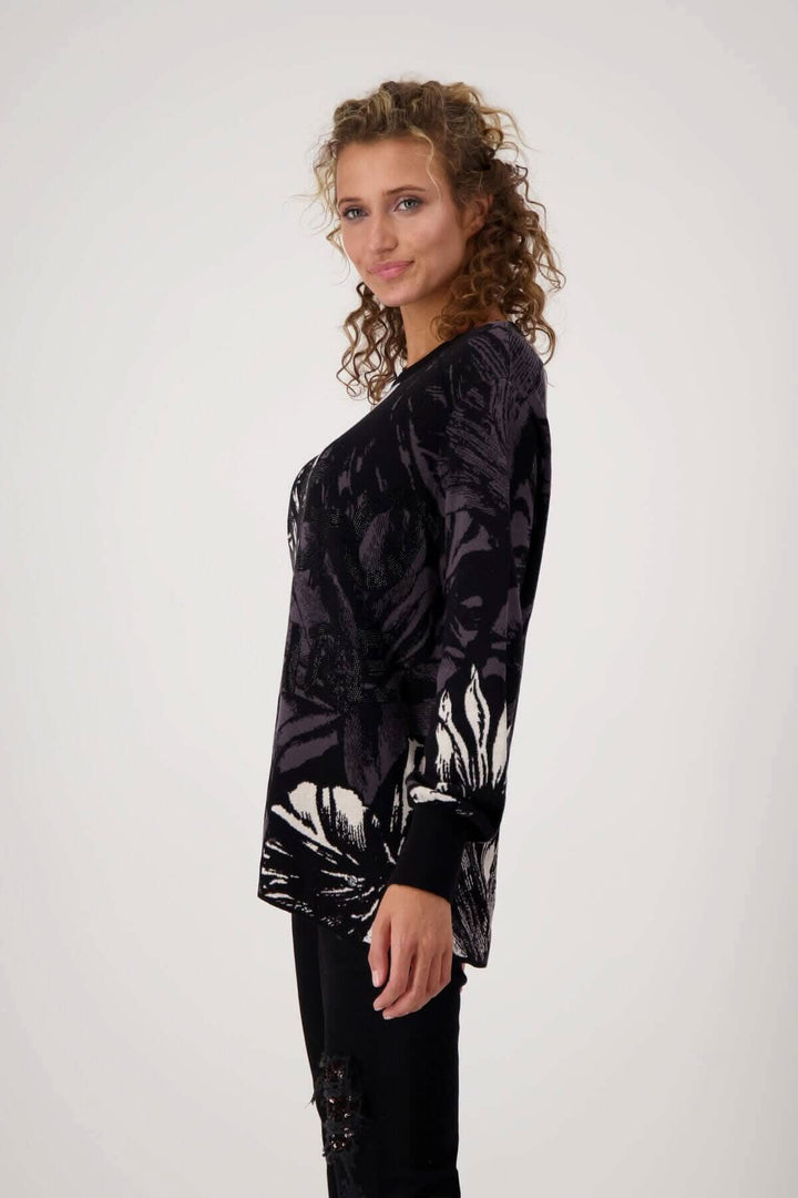 Pull en maille de coton noir à motif floral, coupe droite avec volants aux manches, porté par un modèle.