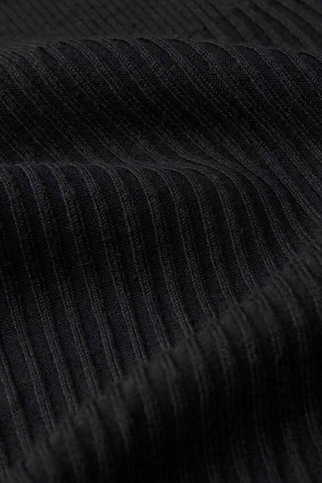 Gros plan sur le tissu côtelé noir du pull tunique, mettant en avant sa texture douce et moderne.
