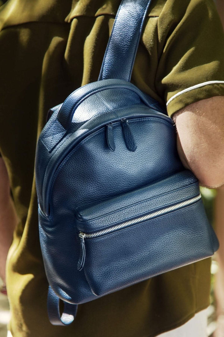 Sac à dos de voyage compact en cuir bleu avec compartiments pratiques, porté sur l&