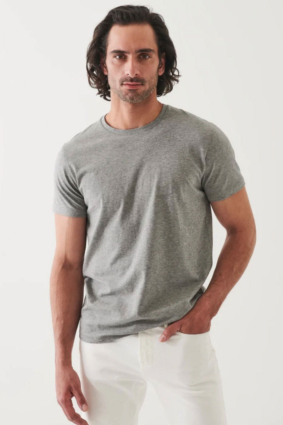 Homme portant un T-shirt basique gris, à la coupe moderne, avec un style minimaliste et un fini légèrement satiné.