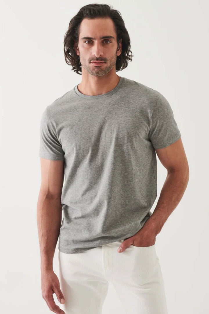 Homme portant un T-shirt basique gris, à la coupe moderne, avec un style minimaliste et un fini légèrement satiné.