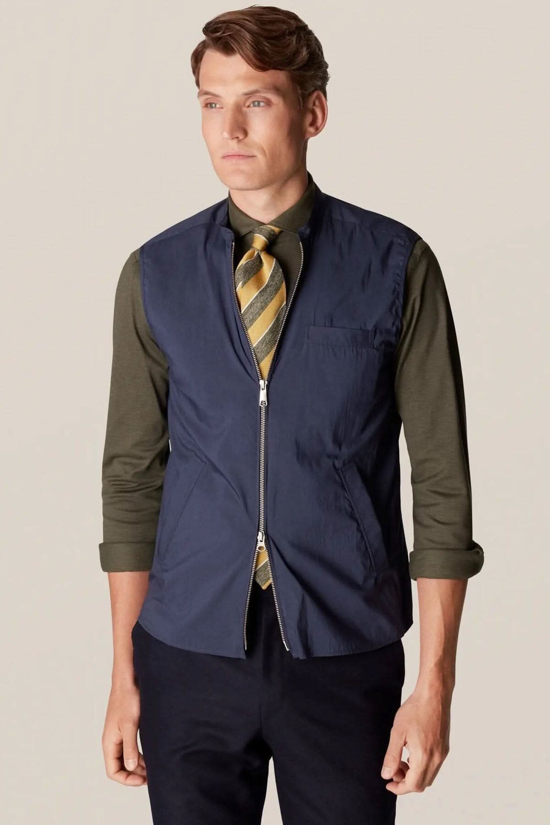 Homme portant une veste sans manches déperlante, élégante et contemporaine, idéale pour la superposition et le style extérieur.