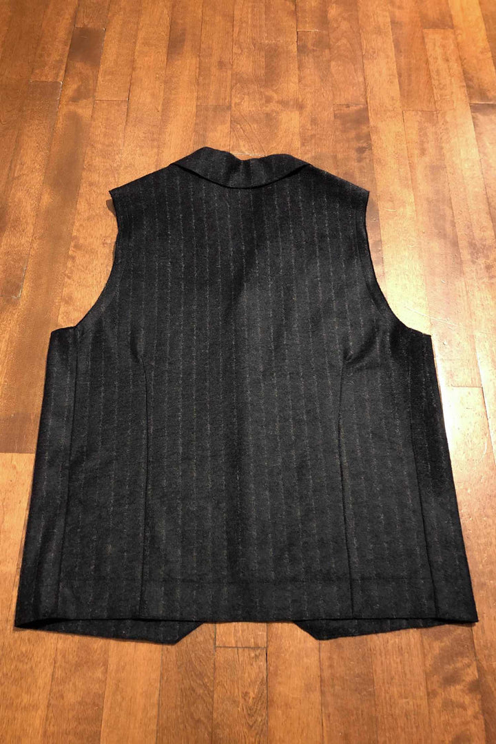 Veste sans manches bleu marine à rayures grises sur fond en bois.